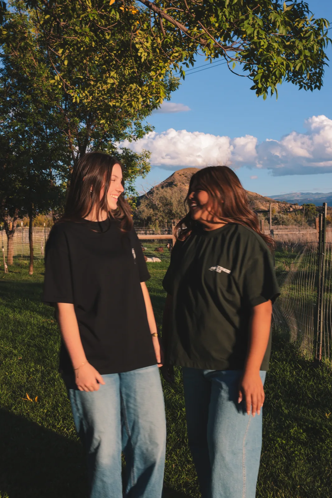 Two students wearing black and olive church tees outdoors