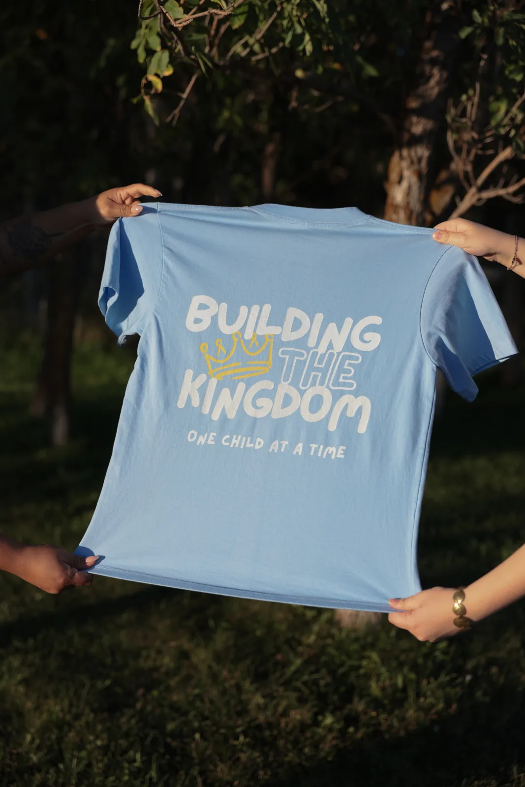 Light blue tee reading Building the Kingdom, One Child at a Time